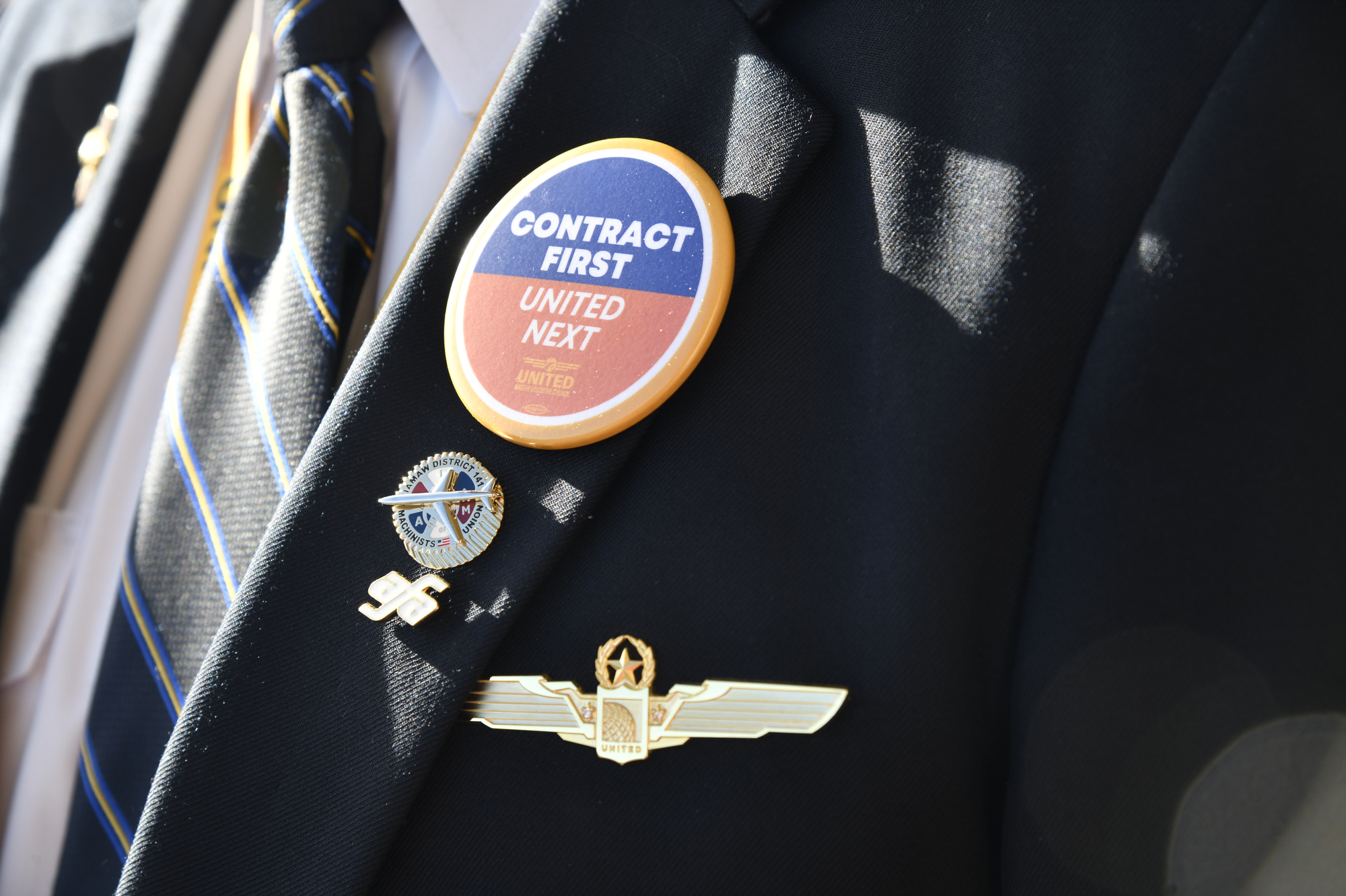 A pilots lapel with a Contract First United Next button 